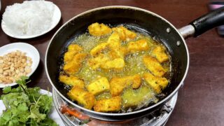 ターメリックで味付けした魚をたっぷりの油で炒め煮。半分揚げている。写真