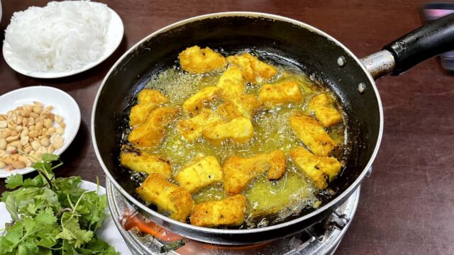 ターメリックで味付けした魚をたっぷりの油で炒め煮。半分揚げている。写真